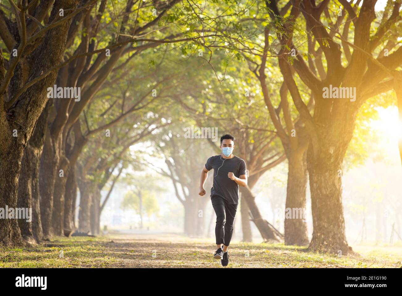 Läufer mit medizinischer Maske und Laufen im Stadtpark Stockfoto