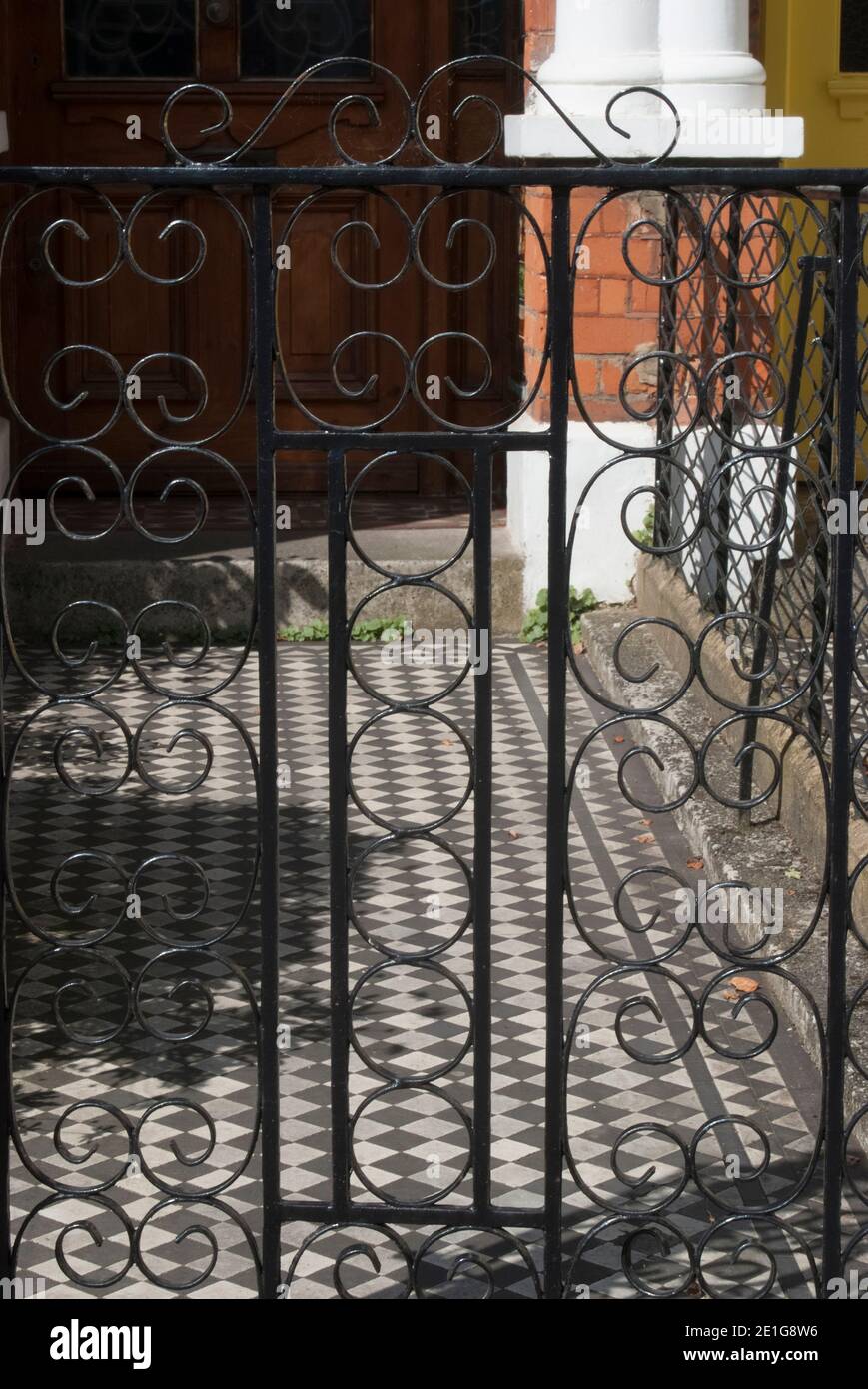 Tor zu einem Haus, schwarze und weiße Fliesen und eine Tür zu einem traditionellen Stadthaus, viktorianische Ära. Stockfoto