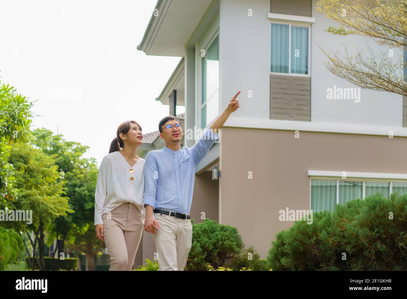 Portrait des asiatischen Paares, das gemeinsam umarmt und vor ihrem neuen Haus glücklich schaut, um neues Leben zu beginnen. Familie, Alter, Haus, Immobilien und Stockfoto