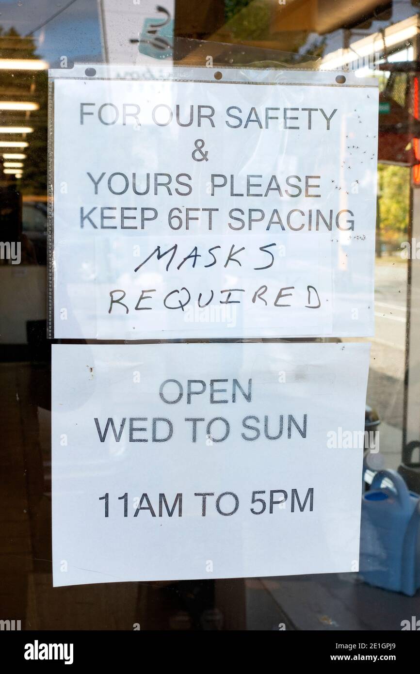 Warnschild für das Tragen von Masken und stehen sechs Fuß auseinander zusammen mit ausgeschilderten Stunden bei der Dairy Queen. St. Paul Minnesota, USA Stockfoto