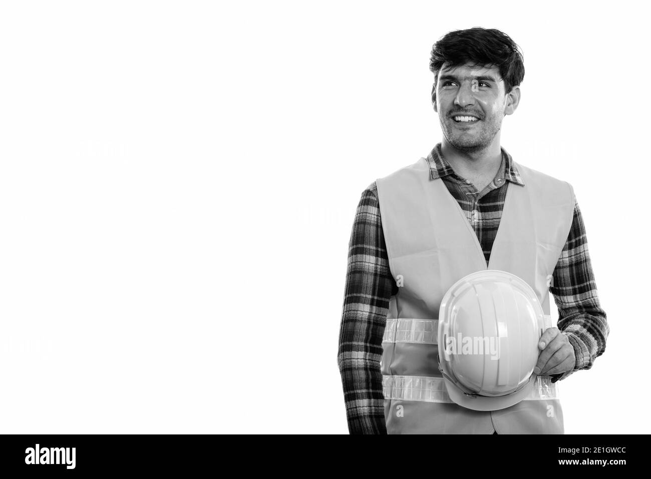 Junge glücklich Persischen mann Bauarbeiter und lächelnd Schutzhelm beim Denken Stockfoto