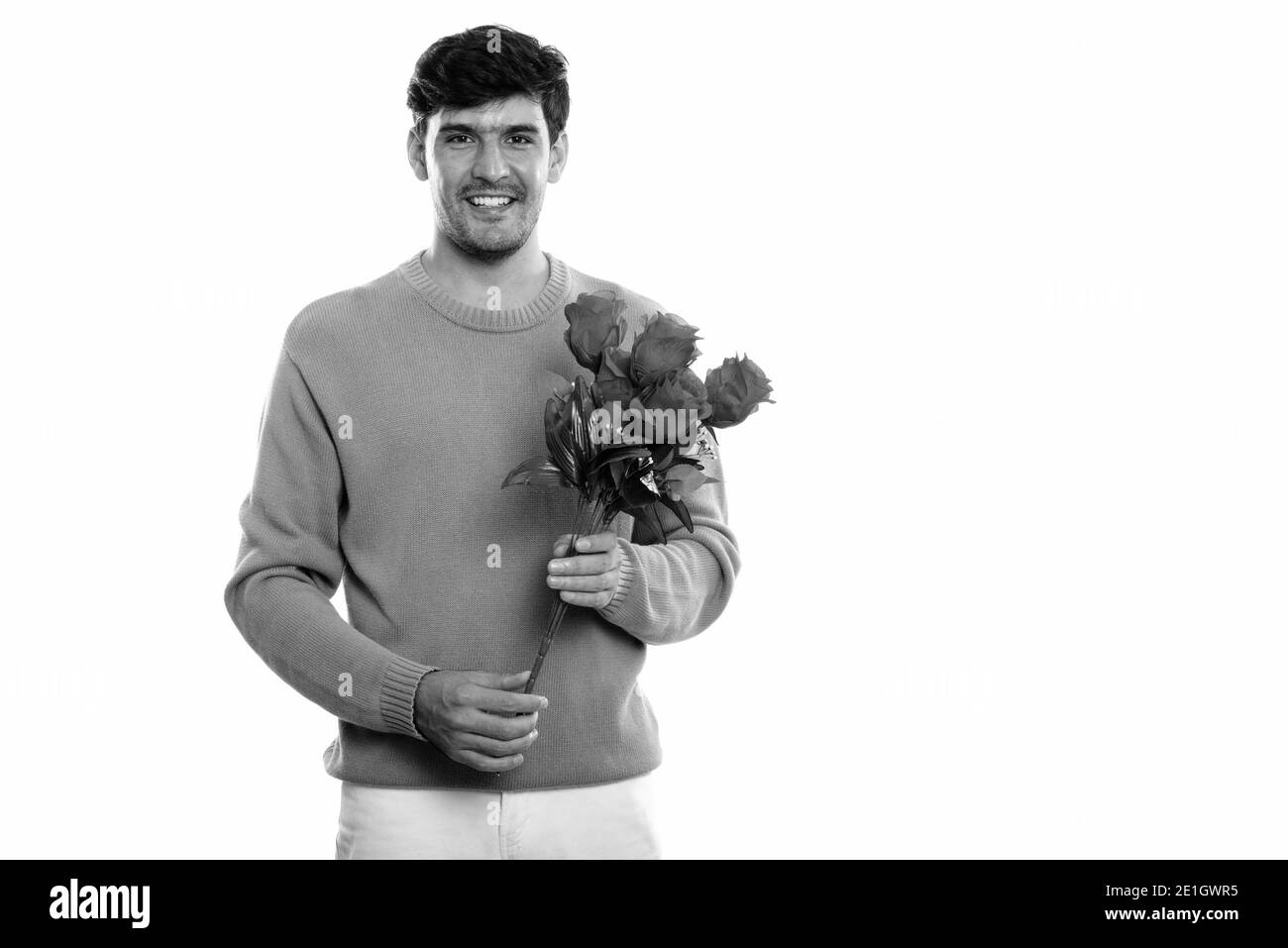 Studio shot der Jungen glücklich Persischen Mann lächelnd, während sie rote Rosen zum Valentinstag bereit Stockfoto