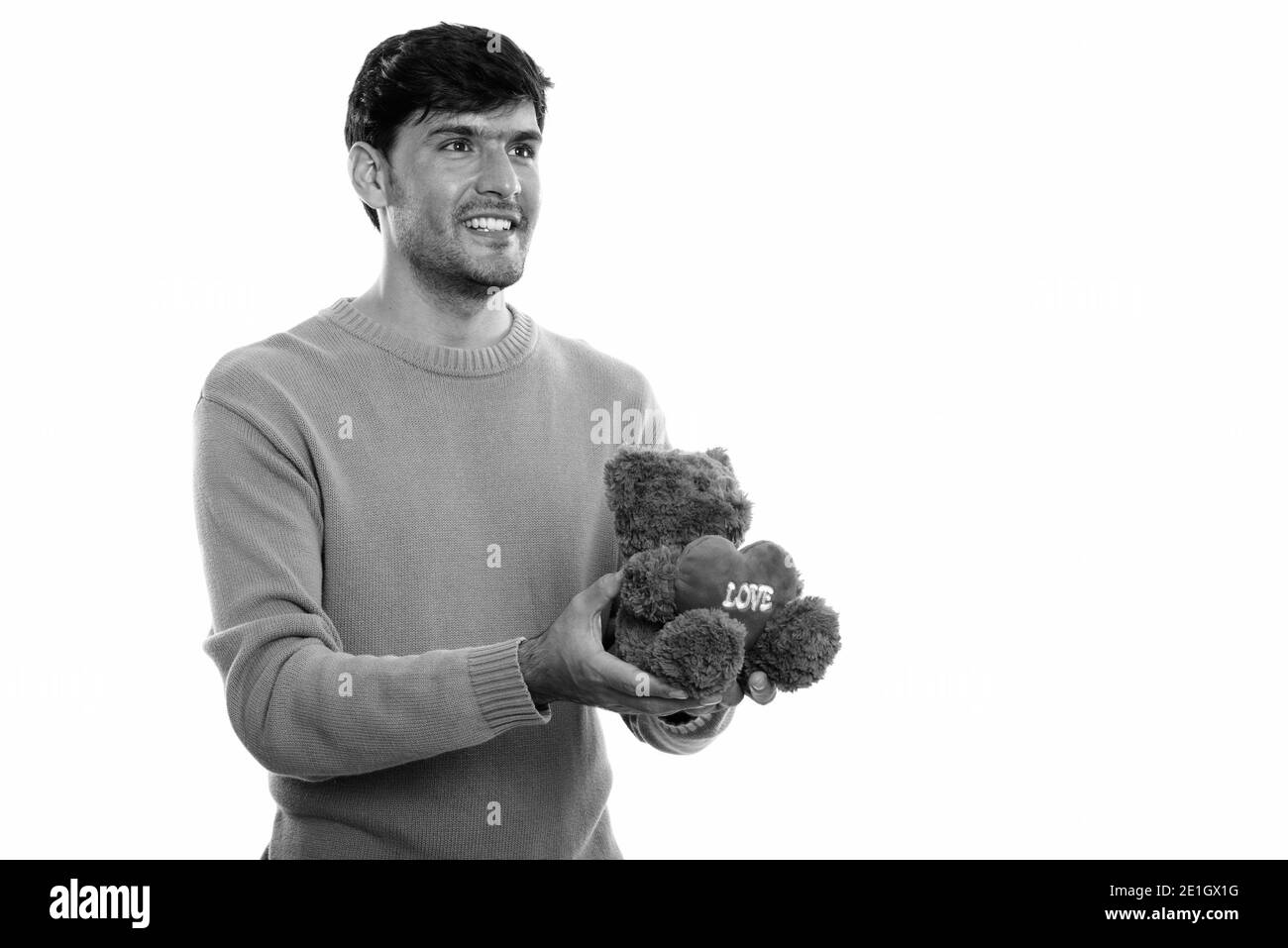 Nachdenklich glücklich Persischen Mann lächelnd, während sie Teddybär mit Herz und Liebe Zeichen für Valentinstag bereit Stockfoto