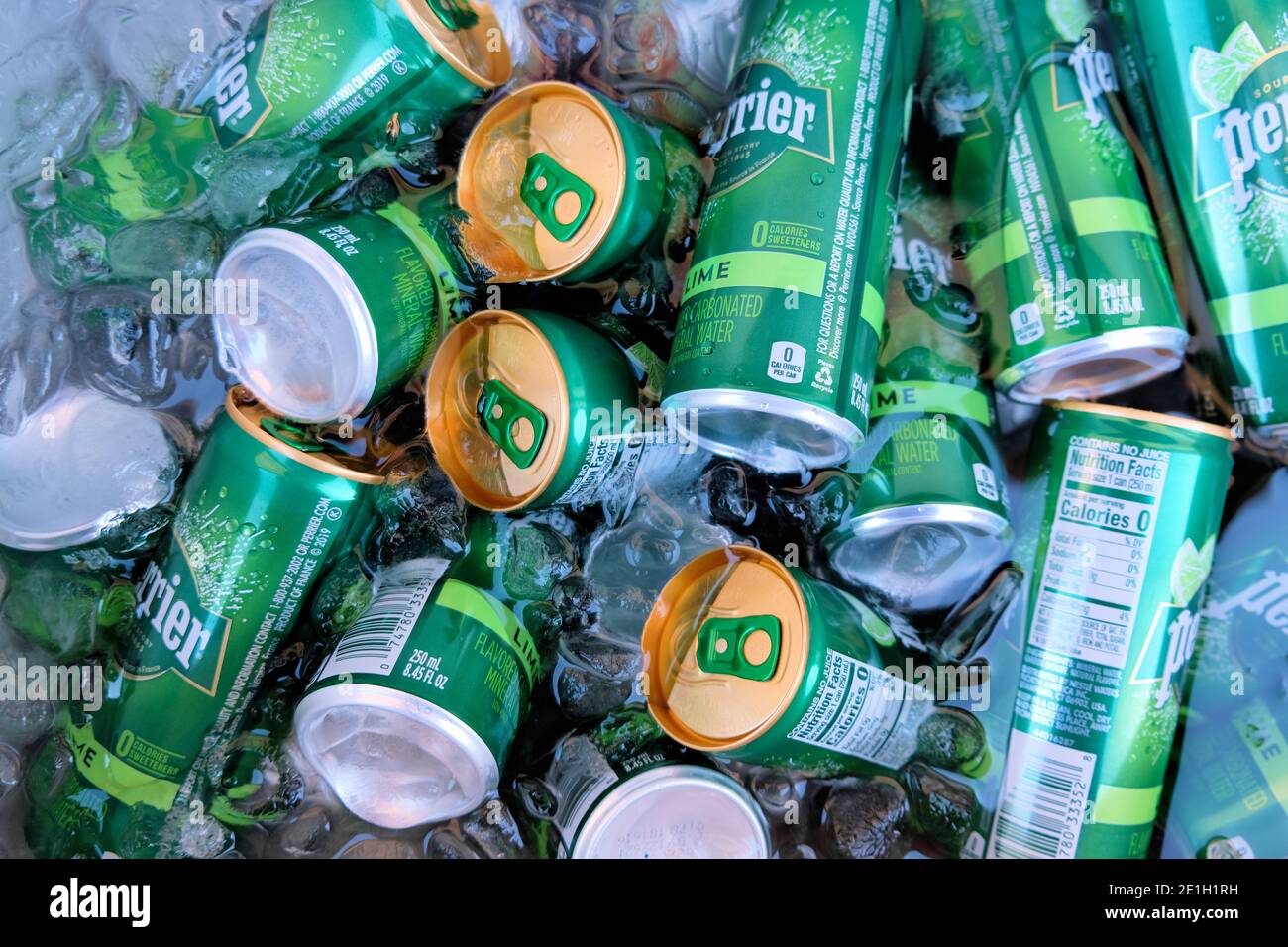 Perrier Limone aromatisierte Mineralwasser in 8.45 Unze schlanke Dosen in einer Eiskiste mit Eis und kaltem Wasser. Stockfoto