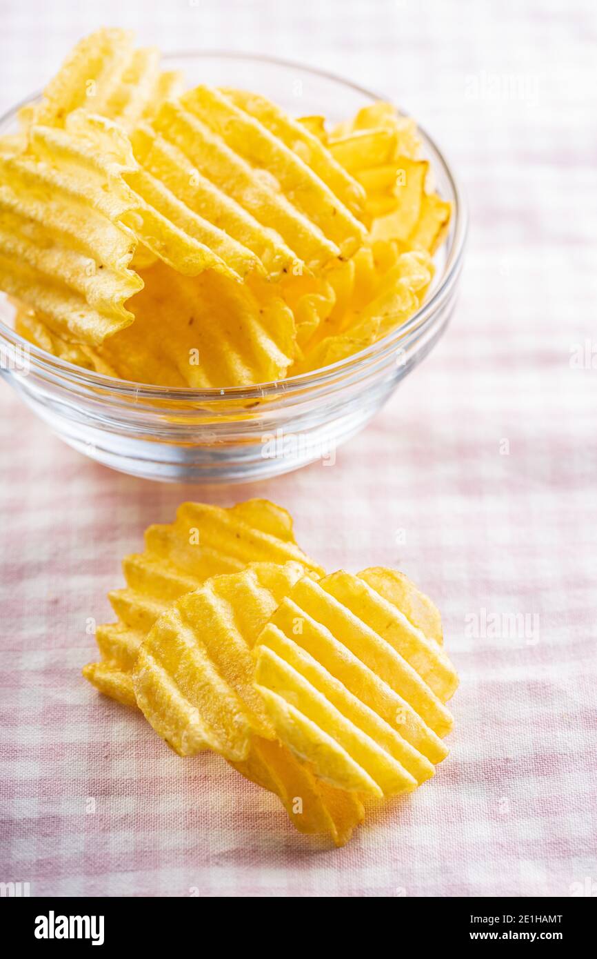 Knusprige Kartoffelchips auf rosa karierter Tischdecke. Stockfoto