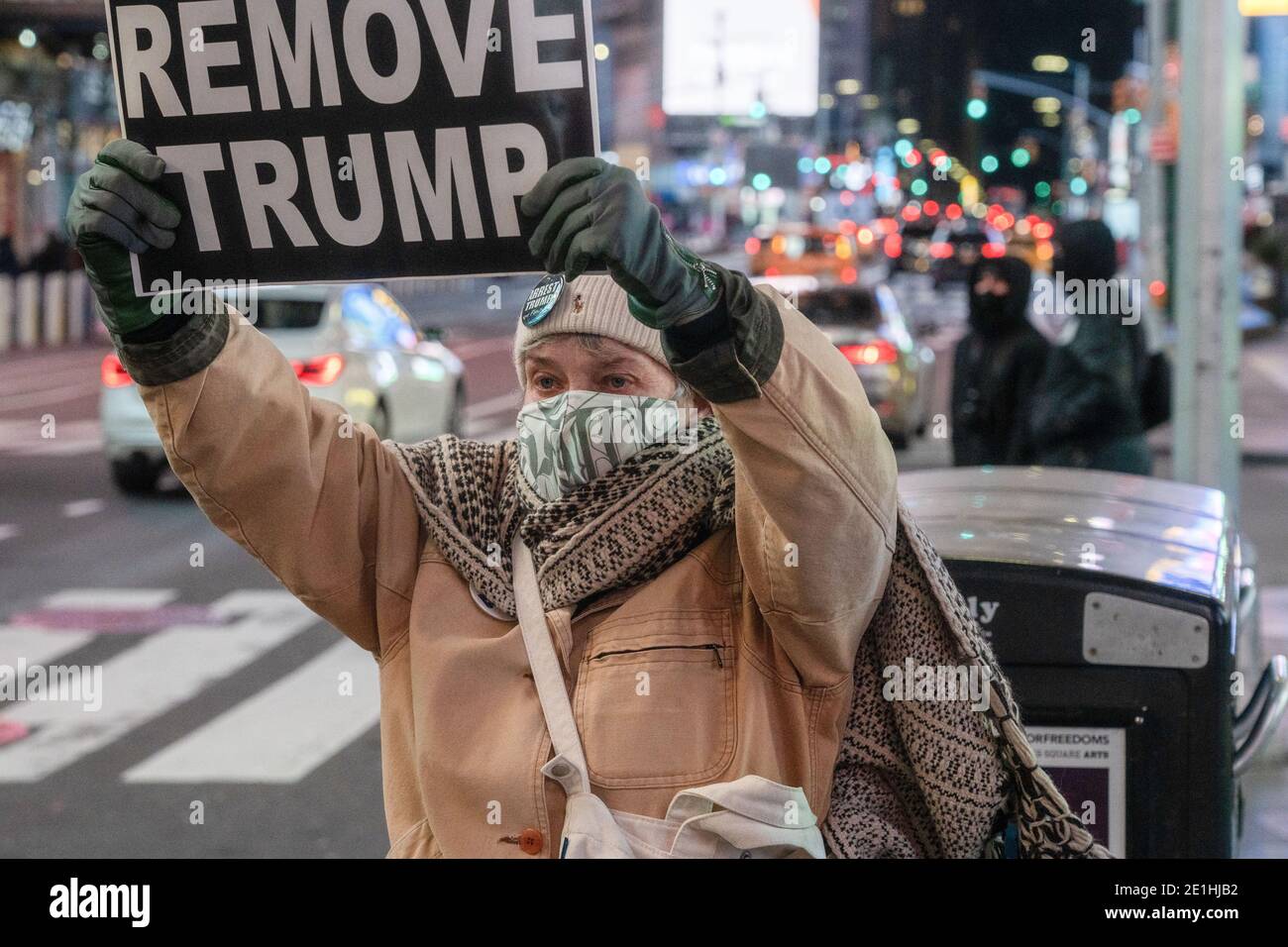 Ein Protestler versucht, eine Reaktion aus vorbeifahrenden Autos zu bekommen, indem er ein Plakat mit der Aufschrift "Remove Trump" während des Protestmarsches am Times Square zeigt.Demonstranten versammelten sich auf dem Times Square und marschierten zum Columbus Circle. Trump International Hotel blockiert den Verkehr auf dem Weg und wurden später mit anderen Demonstranten von Rise and Resist getroffen. Stockfoto