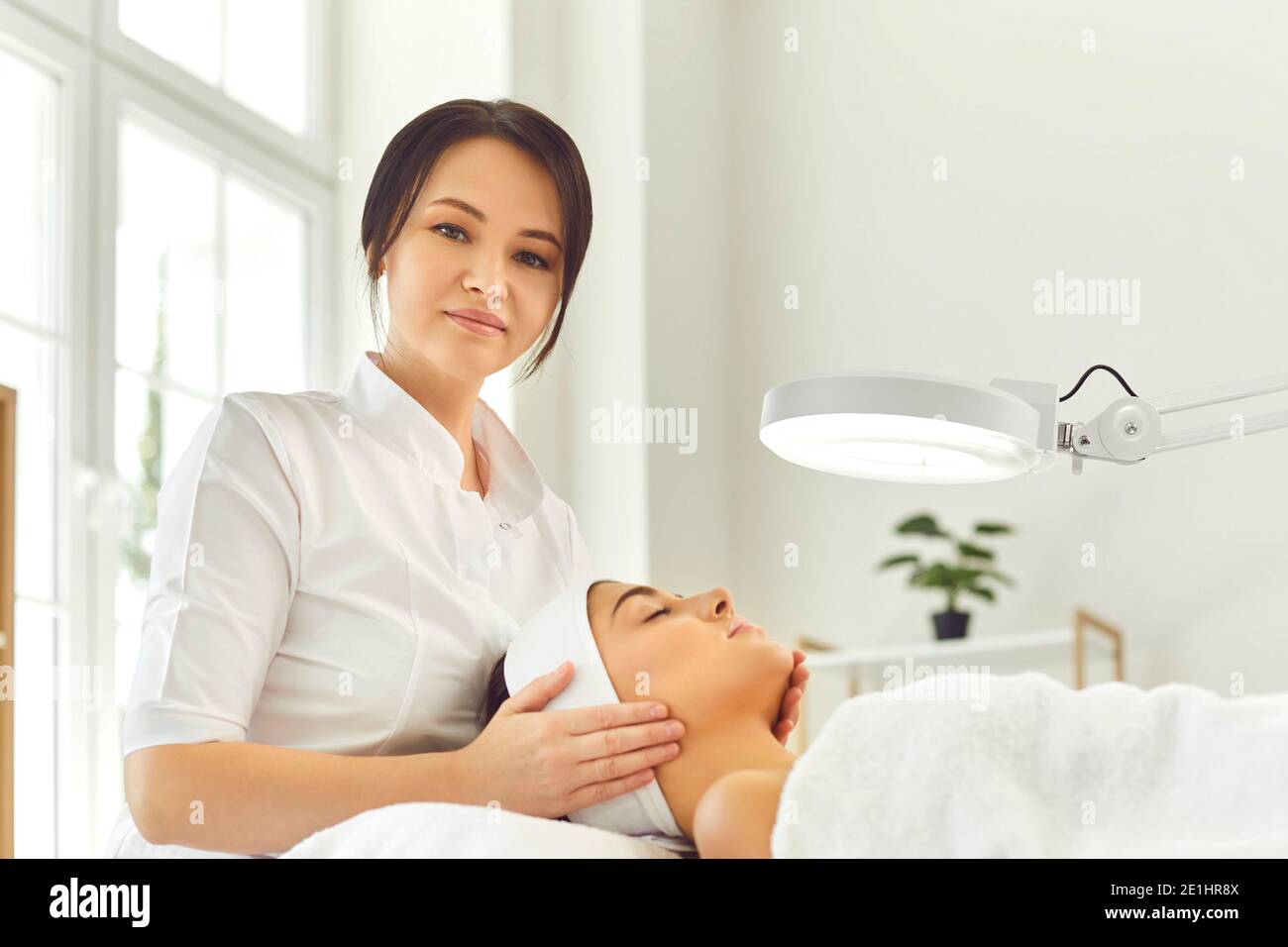 Frau Dermatologe berühren junge Frauen Gesicht während der Überprüfung der Haut oder Massage Stockfoto