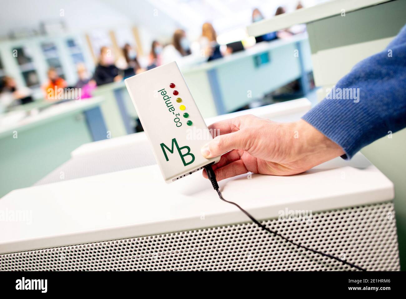 Oldenburg, Deutschland. Dezember 2020. Ein Lehrer hält eine gelb leuchtende CO2-Ampel vor einer Luftfiltereinheit in einem Themenraum des Alten Gymnasiums. Die Schule hat mehrere mobile Luftfilteranlagen angeschafft, um die Konzentration von Aerosolen auch in nicht gut belüfteten Klassenzimmern reduzieren zu können. Quelle: Hauke-Christian Dittrich/dpa/Alamy Live News Stockfoto