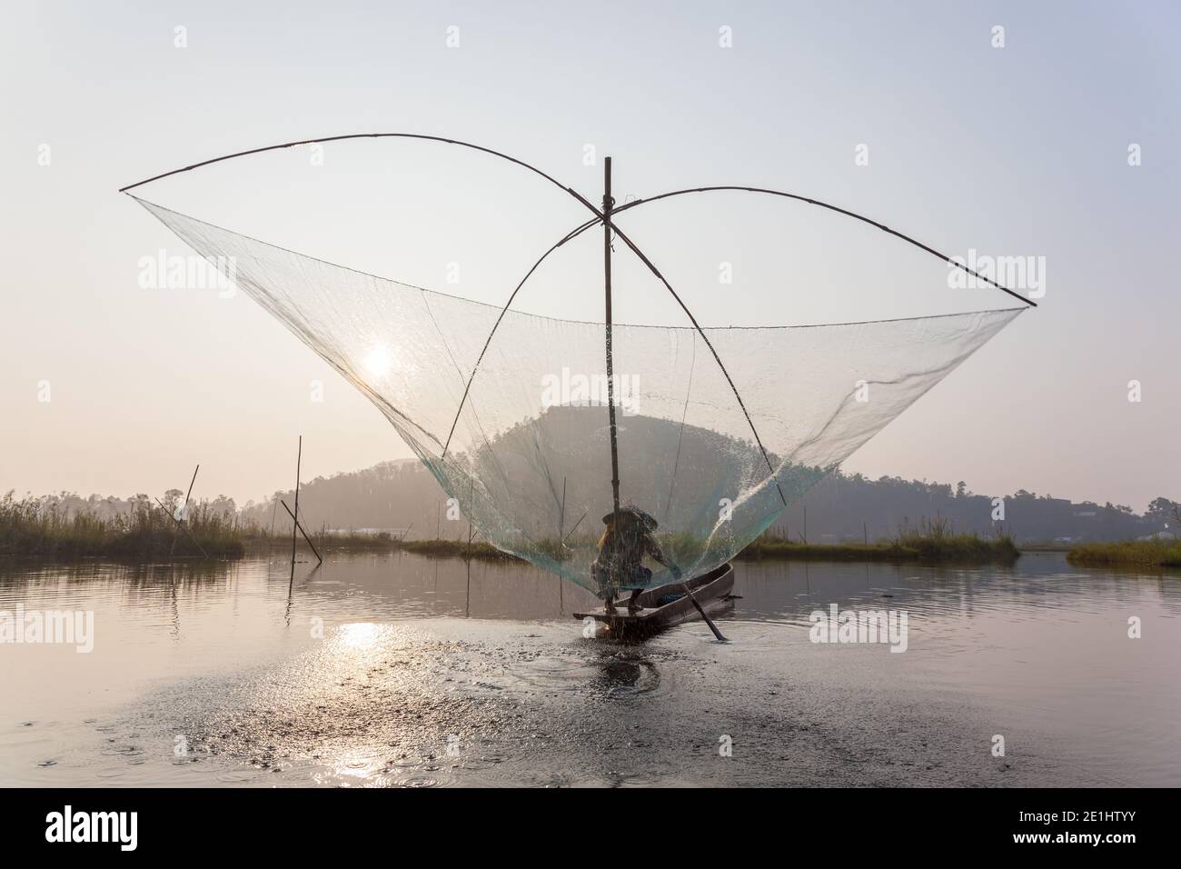 Fischer auf seinem Boot bewegen gewölbte Schwenk Netze über dem Wasser am Loktak See Stockfoto