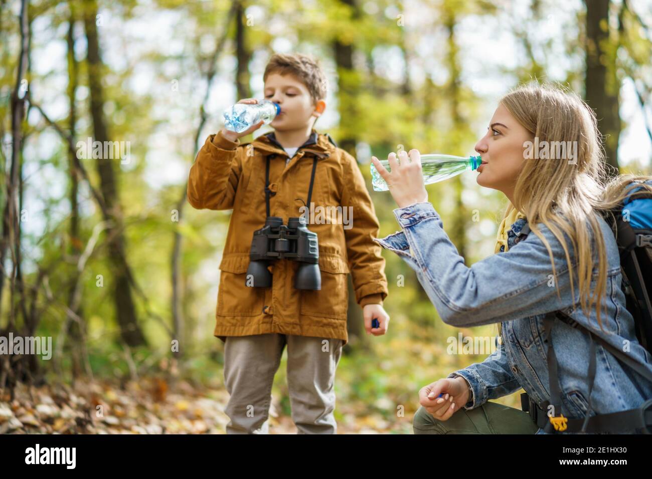Glückliche Mutter und Sohn wandern im Wald. Sie sind Trinkwasser. Stockfoto