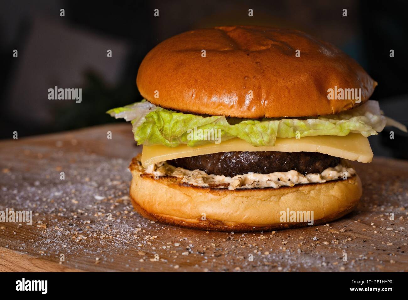 Hausgemachter Gourmet-Cheeseburger mit Romaine-Salat, reifem Cheddar-Käse und Hummus Stockfoto