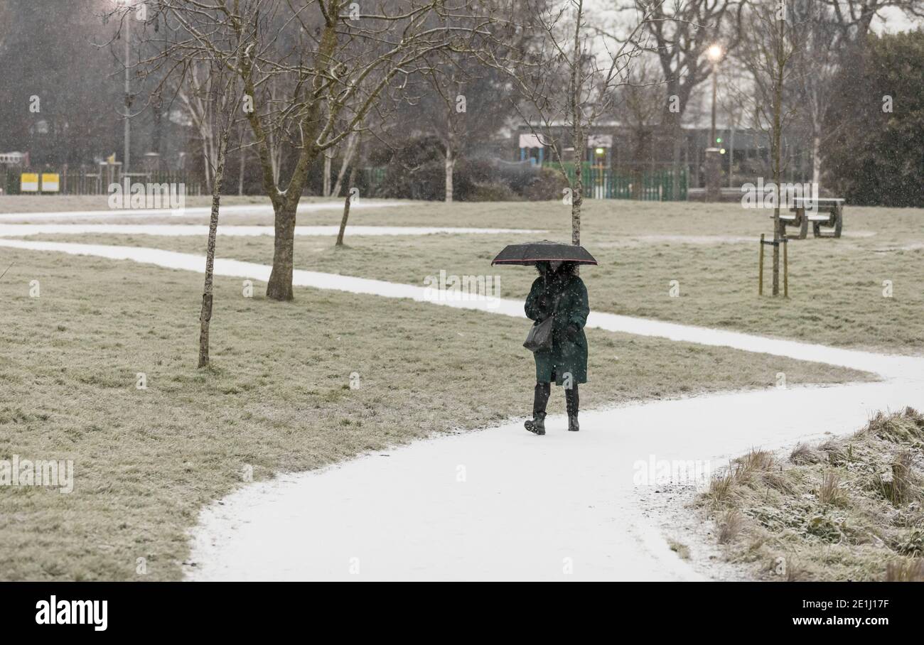 Carrigaline, Cork, Irland. Januar 2021. Schnee beginnt zu fallen, als eine Frau durch den Gemeinschaftspark in Carrigaline, Co. Cork, Irland, geht. - Credit; David Creedon / Alamy Live News Stockfoto