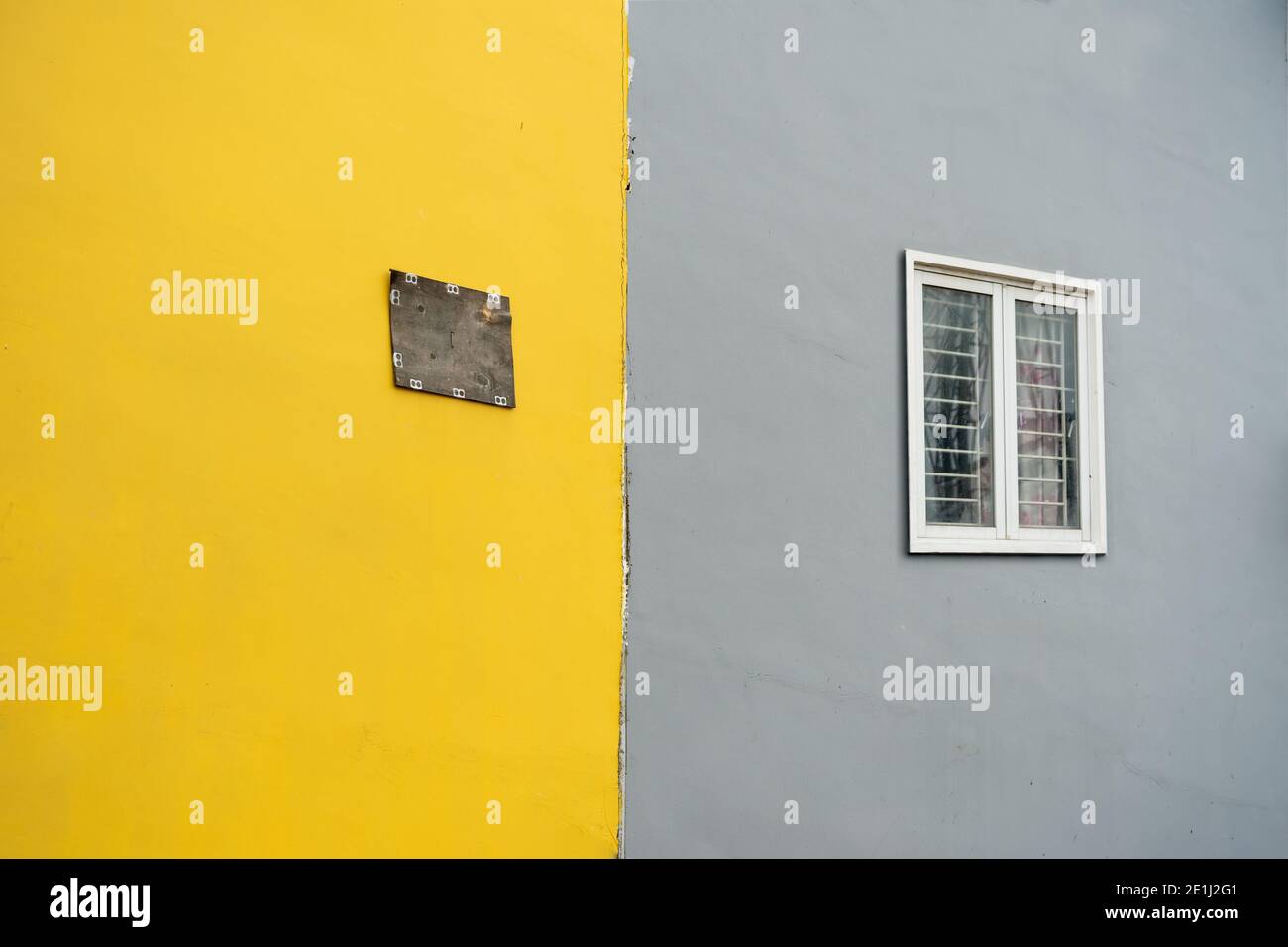 Alte Wand mit Fenster in gelb und grau lackiert Stockfoto