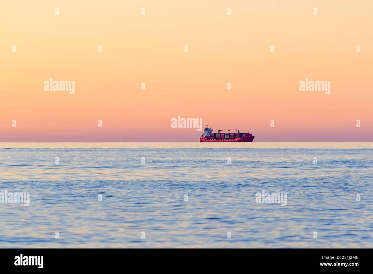 International Container Cargo Schiff am offenen Meereshorizont bei Sonnenuntergang. Internationaler Wassertransport. Seitenansicht. Unscharfe Fotos mit Bewegungsunschärfe. Stockfoto