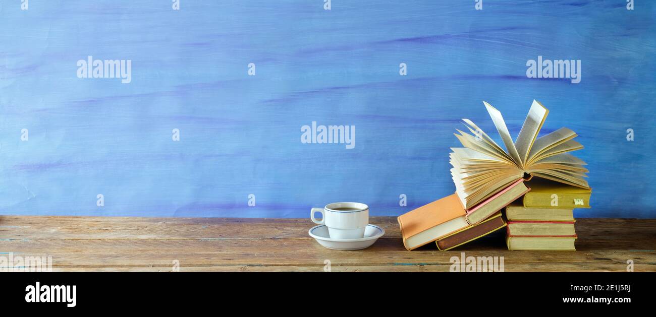 Stapel von Büchern, ein Buch und eine Tasse Kaffee.Bildung, Lesen, Literatur, Home Office, Panorama mit großen Kopieplatz Stockfoto