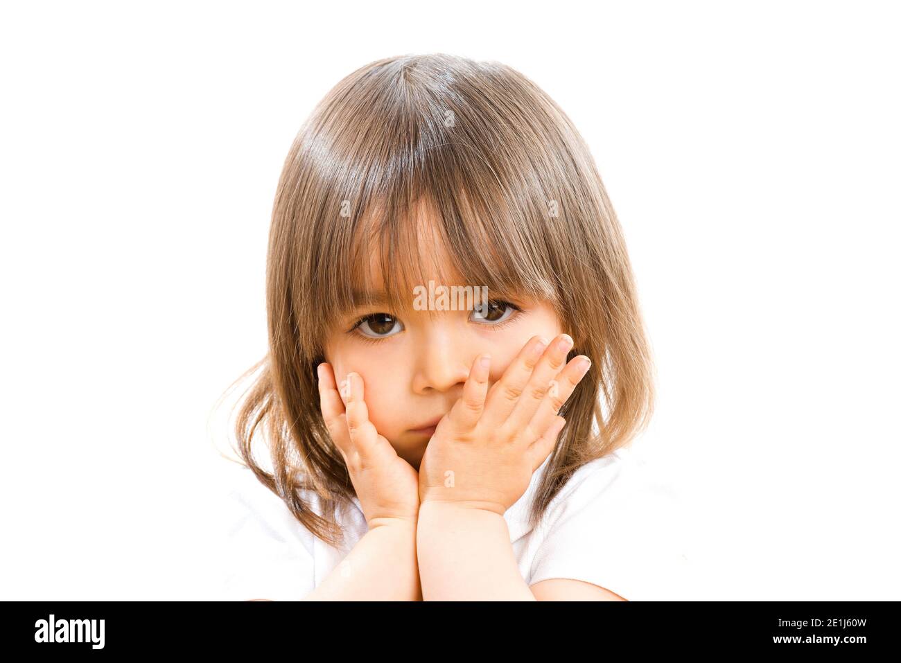 Zwei Jahre altes Mädchen mit den Händen vor dem Gesicht auf weißem Hintergrund. Stockfoto