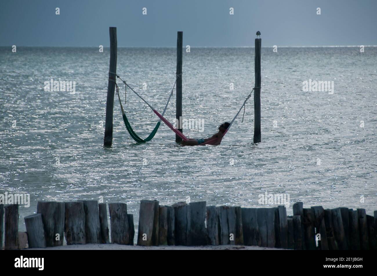 Silhouette eines Touristen auf einer Hängematte in der Karibik Meer, entspannen und genießen Sie das Panorama der Insel Holbox, Mexiko Stockfoto