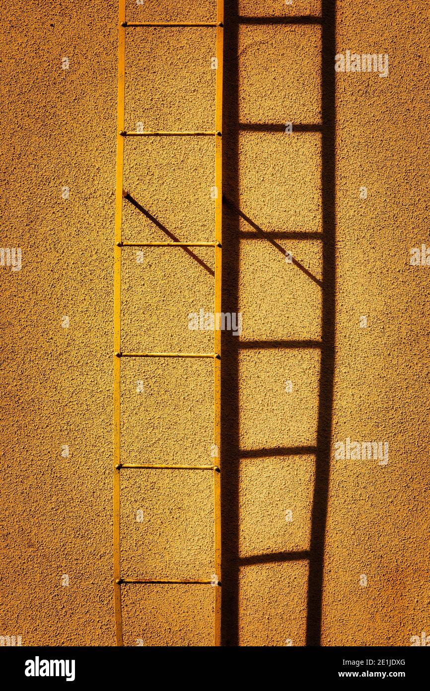 Die Leiter und ihr Schatten durch ein gelbes Gebäude. Stockfoto