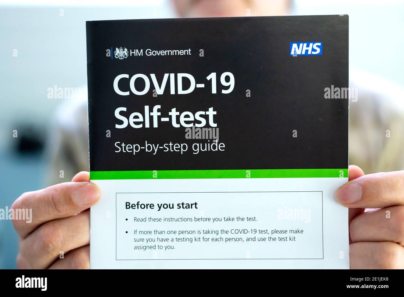 Ein Mann hält Covid-19 Selbsttest Schritt-für-Schritt-Anleitung vor sich. Das Handbuch enthält Anweisungen zur Durchführung des Covid-19-Abstrichtests. Stockfoto