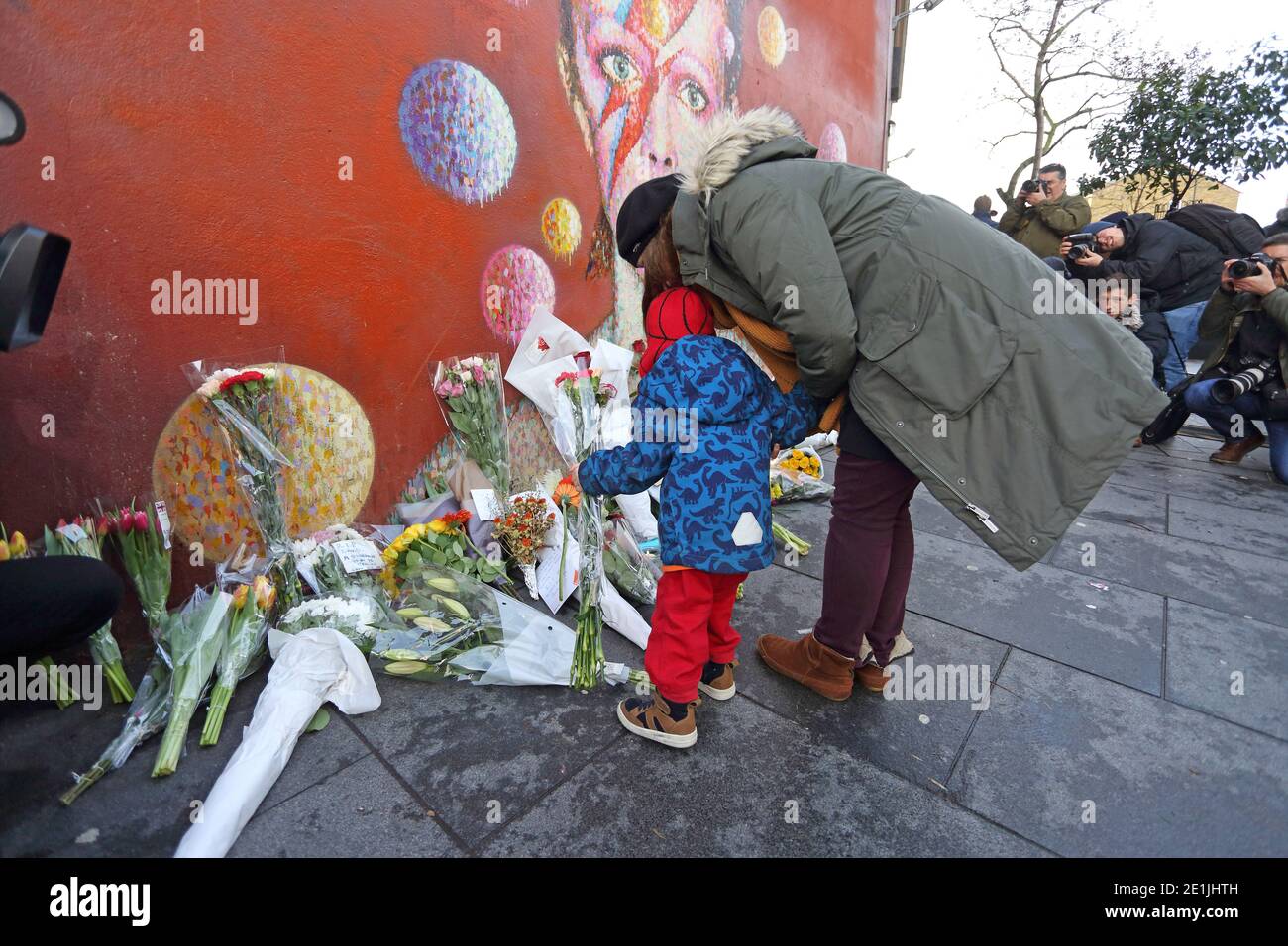 London, Großbritannien. 11th. Januar 2016. Fans versammeln sich am David Bowie Wandgemälde in Brixton, im Süden Londons, zu einer abendlichen Mahnwache, um Blumen zu legen Stockfoto