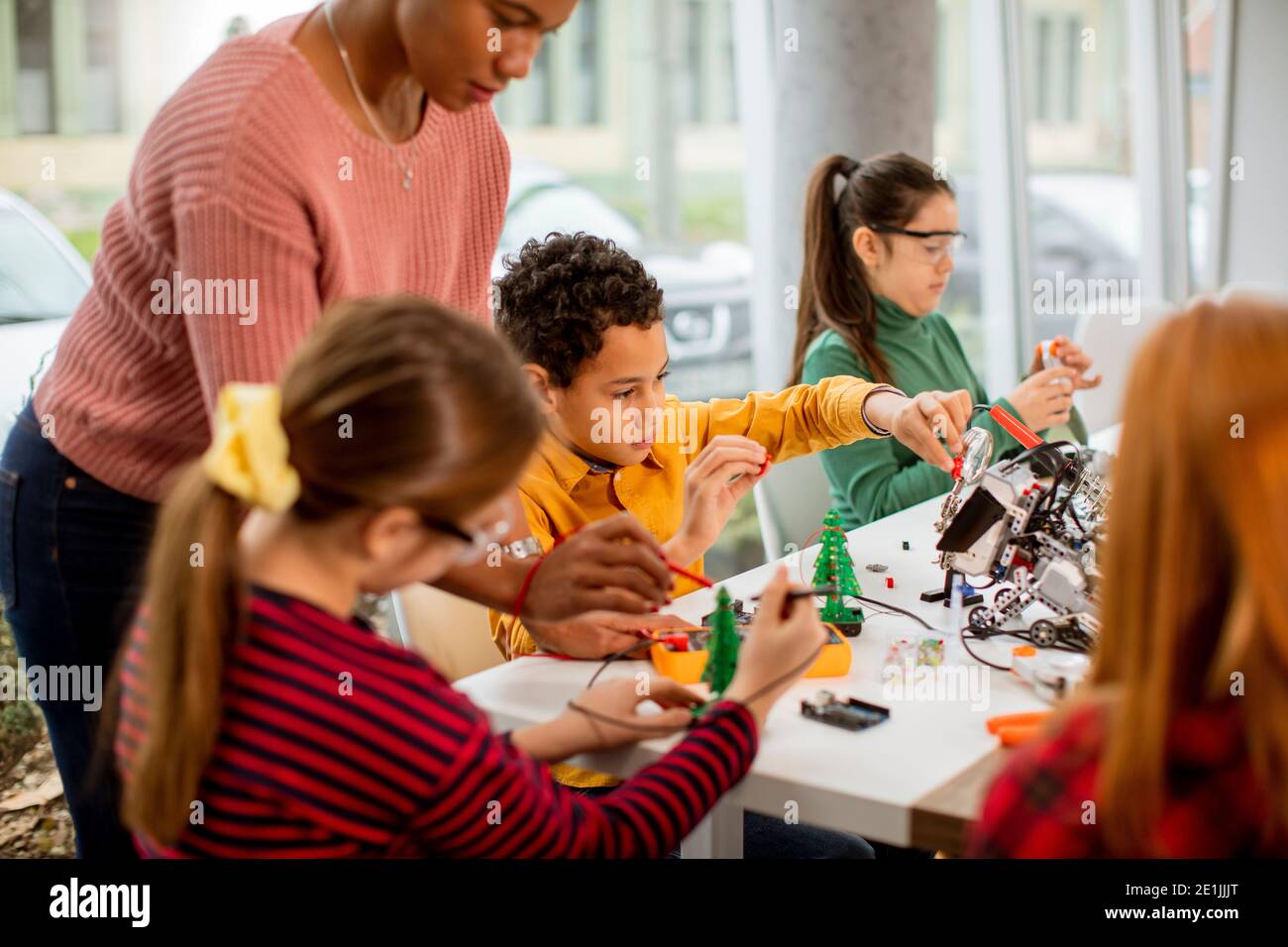 Smiley afroamerikanische Wissenschaftlerin mit Gruppe von Kindern Programmierung von elektrischen Spielzeugen und Robotern im Klassenzimmer der Robotik Stockfoto