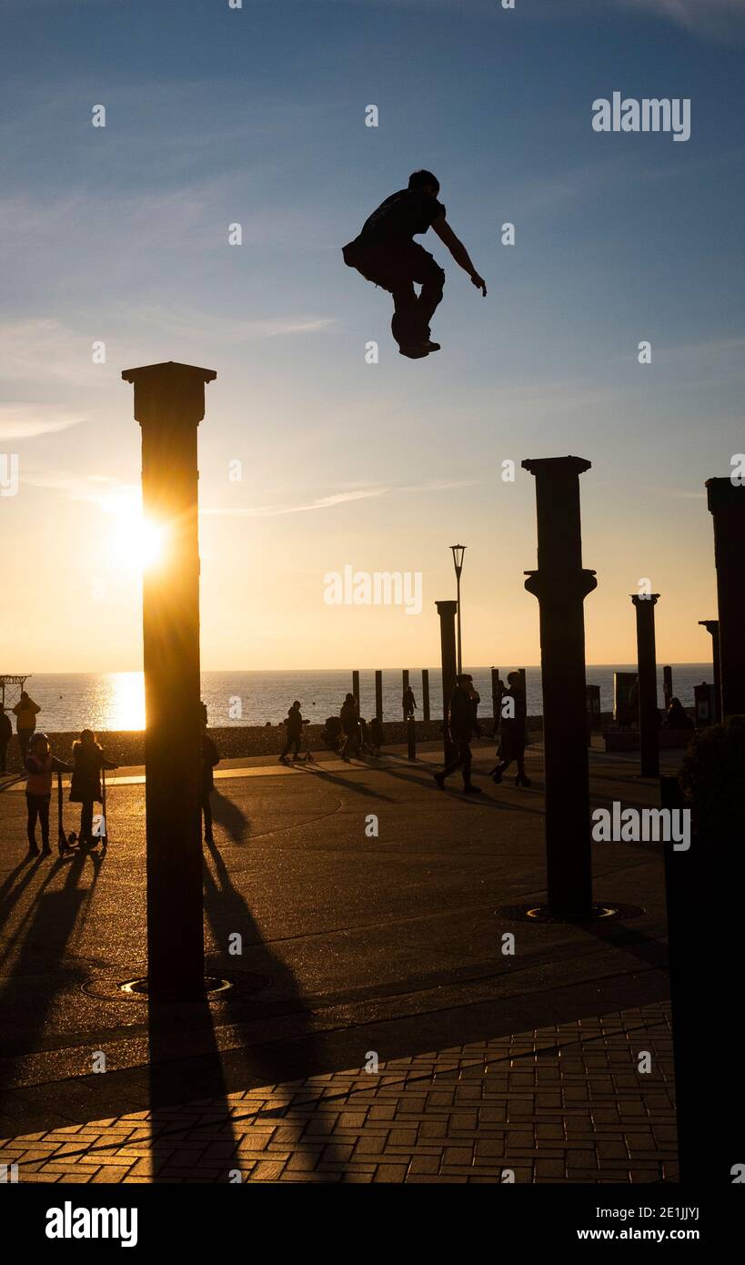 Brighton UK 7. Januar 2021 - Free Runners springen von Säule zu Säule der Golden Spiral Kunstinstallation in der Nähe des West Pier an der Küste von Brighton, während die Sonne nach einem schönen Tag an der Südküste untergeht : Credit Simon Dack / Alamy Live News Stockfoto