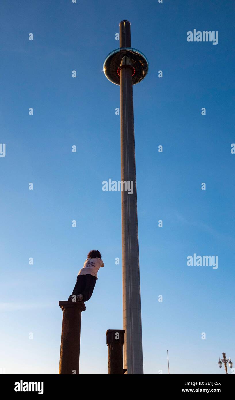 Brighton UK 7. Januar 2021 - Free Runners springen von Säule zu Säule der Golden Spiral Kunstinstallation vom BAi360 Turm an der Küste von Brighton, während die Sonne nach einem schönen Tag an der Südküste untergeht : Credit Simon Dack / Alamy Live News Stockfoto