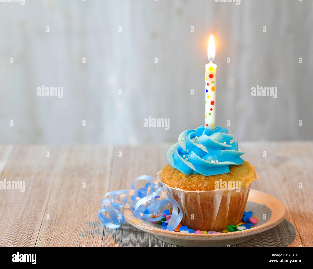 Cupcake mit Kerze und blauem Zuckerguss zum Geburtstag Stockfoto
