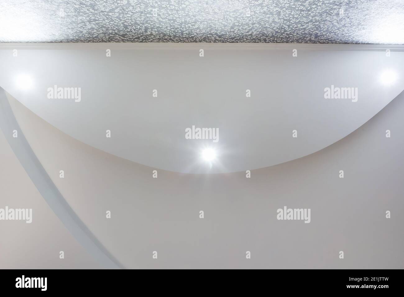 Detail der Eckdecke mit aufwändigen Stuckverzierungen. Abgehängte Decke und Trockenbau in leerem Raum in Wohnung oder Haus. Dehnbare Decke Stockfoto