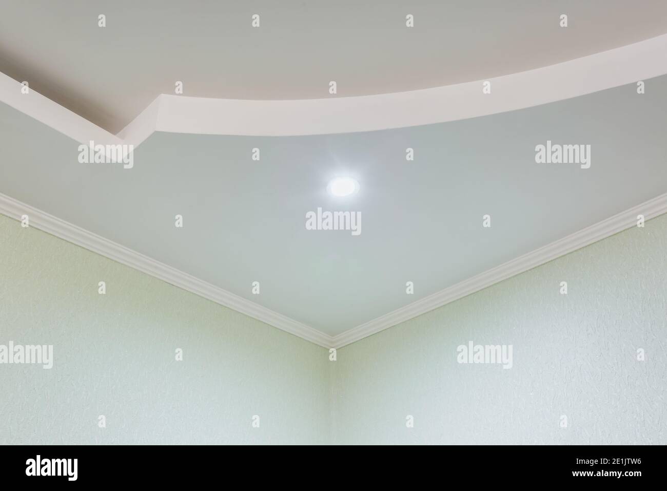 Detail der Eckdecke mit aufwändigen Stuckverzierungen. Abgehängte Decke und Trockenbau in leerem Raum in Wohnung oder Haus. Dehnbare Decke Stockfoto