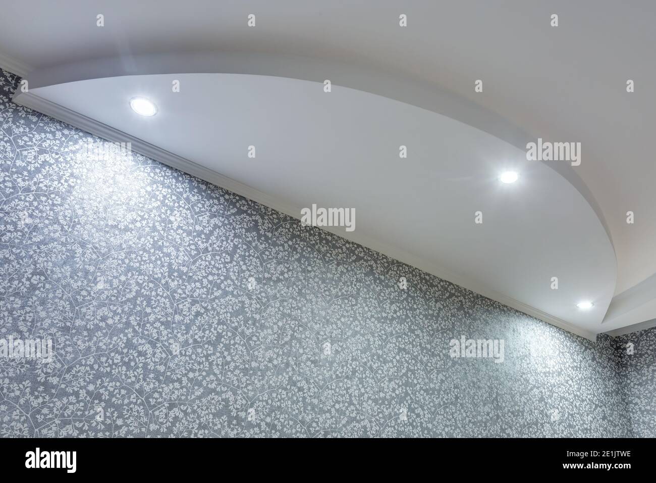 Detail der Eckdecke mit aufwändigen Stuckverzierungen. Abgehängte Decke und Trockenbau in leerem Raum in Wohnung oder Haus. Dehnbare Decke Stockfoto