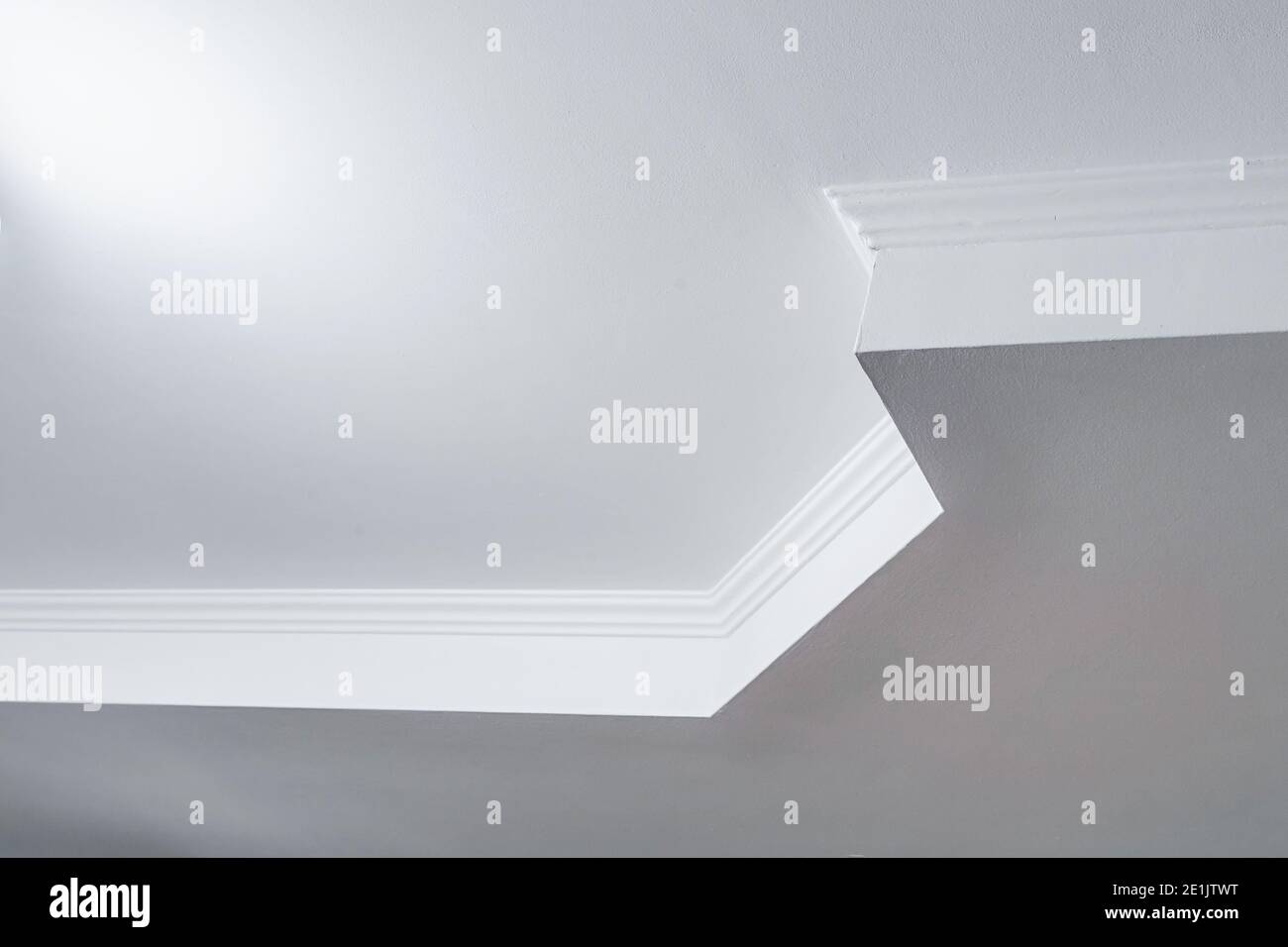 Detail der Eckdecke mit aufwändigen Stuckverzierungen. Abgehängte Decke und Trockenbau in leerem Raum in Wohnung oder Haus. Dehnbare Decke Stockfoto