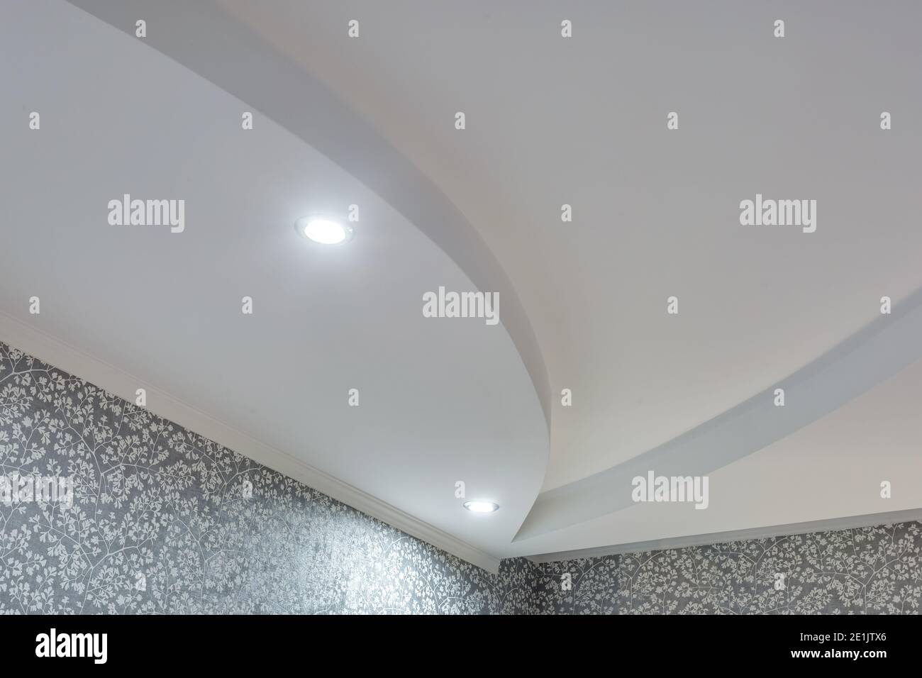 Detail der Eckdecke mit aufwändigen Stuckverzierungen. Abgehängte Decke und Trockenbau in leerem Raum in Wohnung oder Haus. Dehnbare Decke Stockfoto