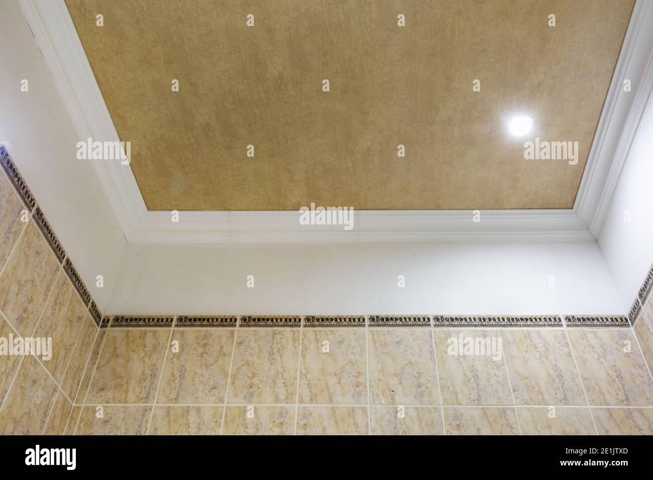 Detail der Eckdecke mit aufwändigen Stuckverzierungen. Abgehängte Decke und Trockenbau in leerem Raum in Wohnung oder Haus. Dehnbare Decke Stockfoto