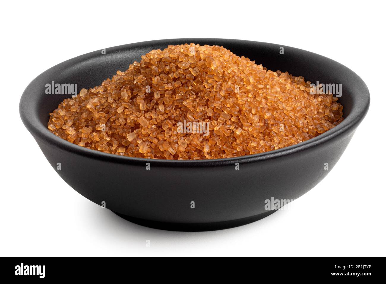 Dunkelbrauner Granulatzucker in schwarzer Keramikschale auf Weiß isoliert. Stockfoto