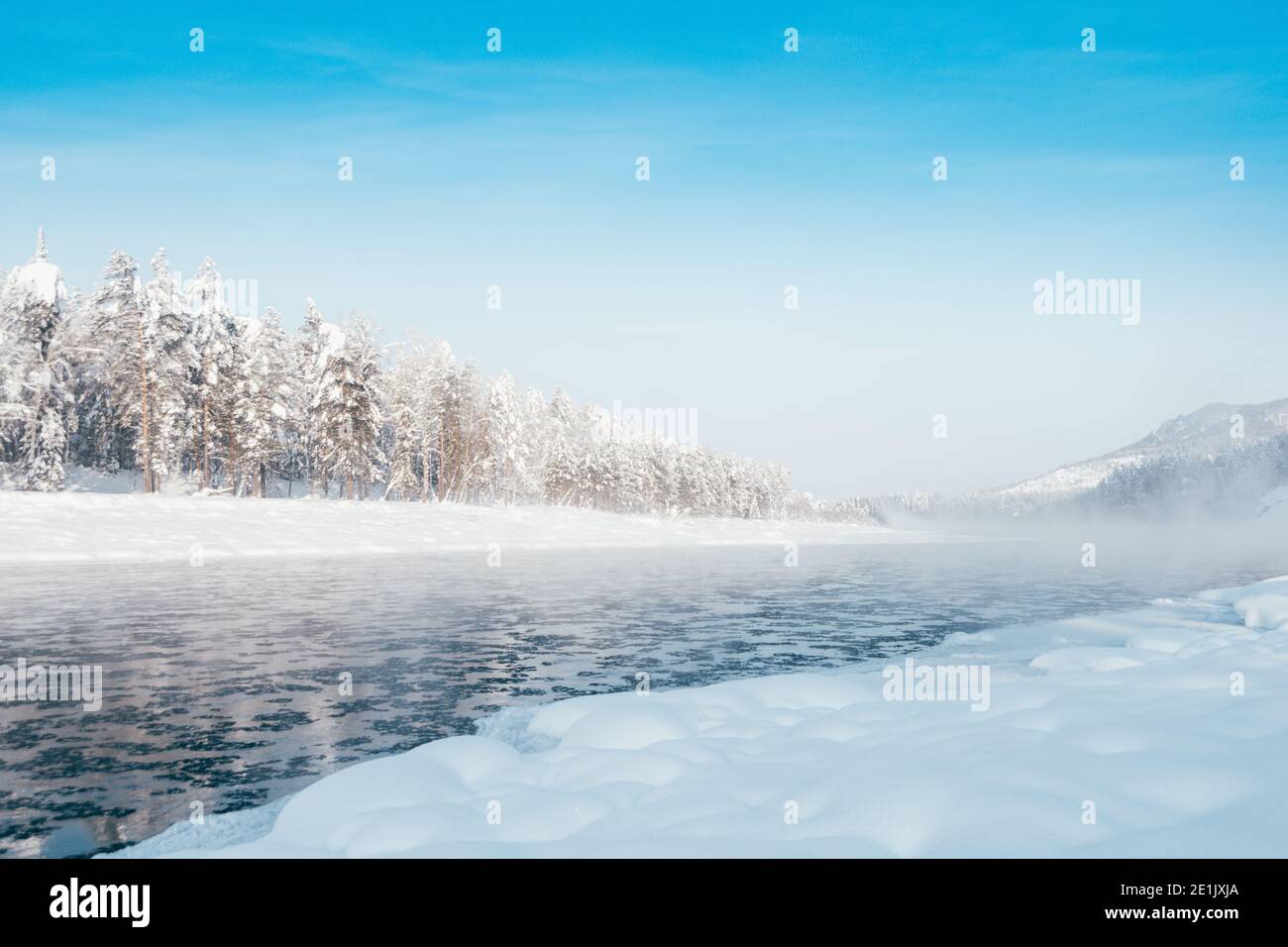 Winter Fluss mit frostigen Nebel über dem Wasser. Schneebäume am Ufer. Stockfoto