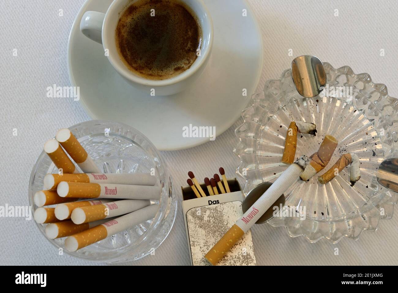 Zigaretten, Streichhölzer und eine Tasse Kaffee auf einem Tisch Stockfoto