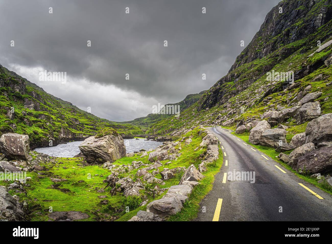 Schmale kurvenreiche Straße, See und Bach mit Steinbrücke im grünen Tal, Gap of Dunloe im Black Valley, Ring of Kerry, County Kerry, Irland Stockfoto