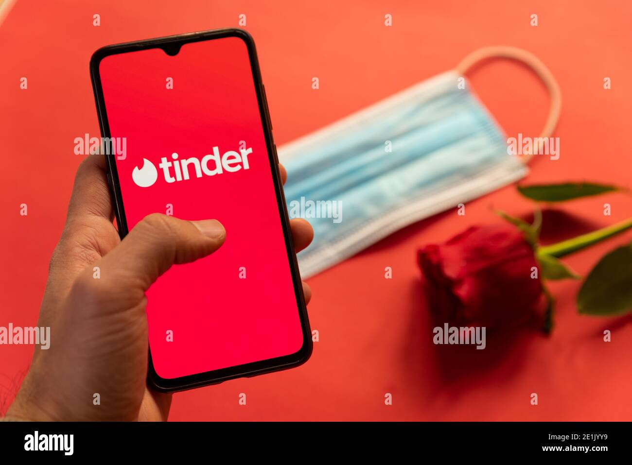 London, UK - 6. januar 2021: tinder Dating App Logo auf Handy mit Gesichtsmaske und roter Rose. Konzept der Datierung während covid19 Pandemie Stockfoto