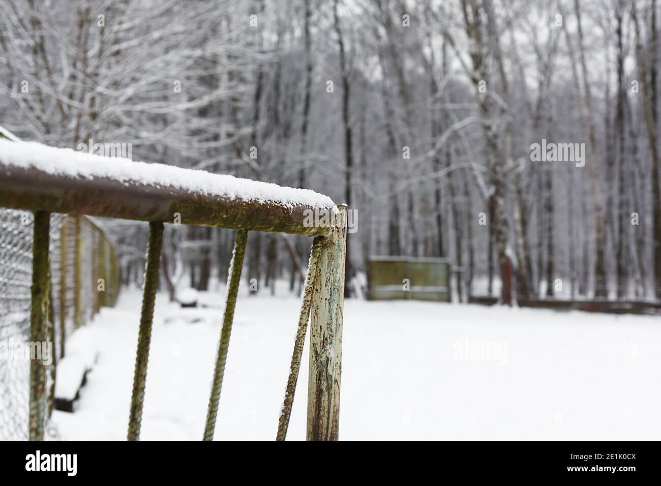 Rostig metallisches Tor mit weißem Schnee bedeckt mit verschneiten Wald auf einem Hintergrund. Eintritt in einen Winterhof Stockfoto