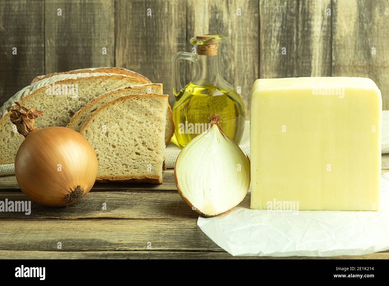 Käse mit Brot und Zwiebeln auf einem Holztisch. Mittelalterliches Essen. Scheibe Brot mit frischem Käse Stockfoto