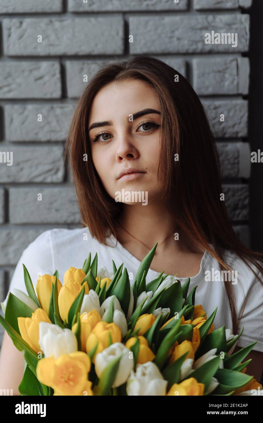 Porträt des Mädchens mit Blumenstrauß aus weißen und gelben Tulpen. Frau mit Tulpen. Internationaler Frauentag Stockfoto