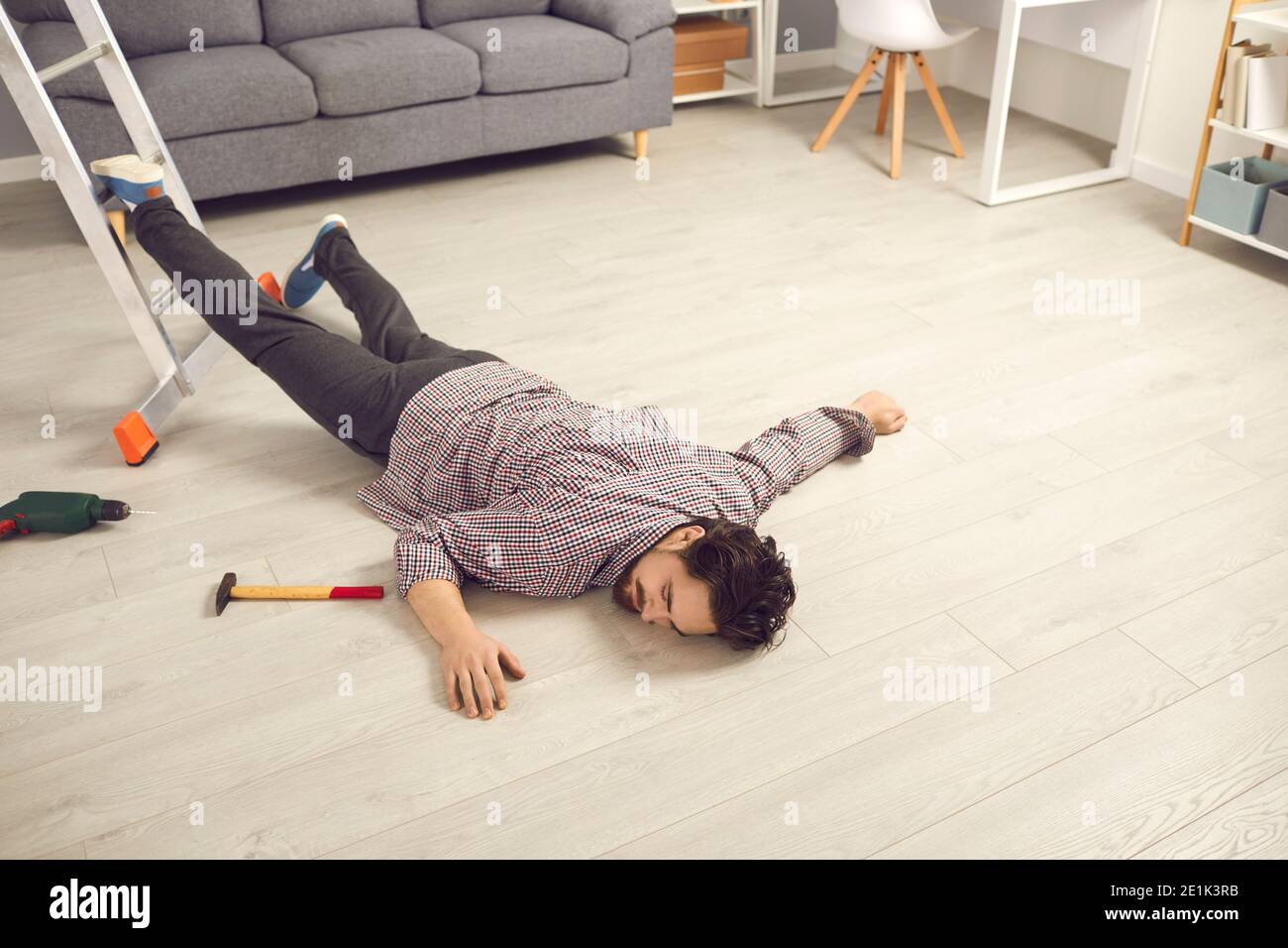Junger Mann, der bei Hausreparaturen von der Leiter fiel Bewusstlos auf dem Boden liegen Stockfoto