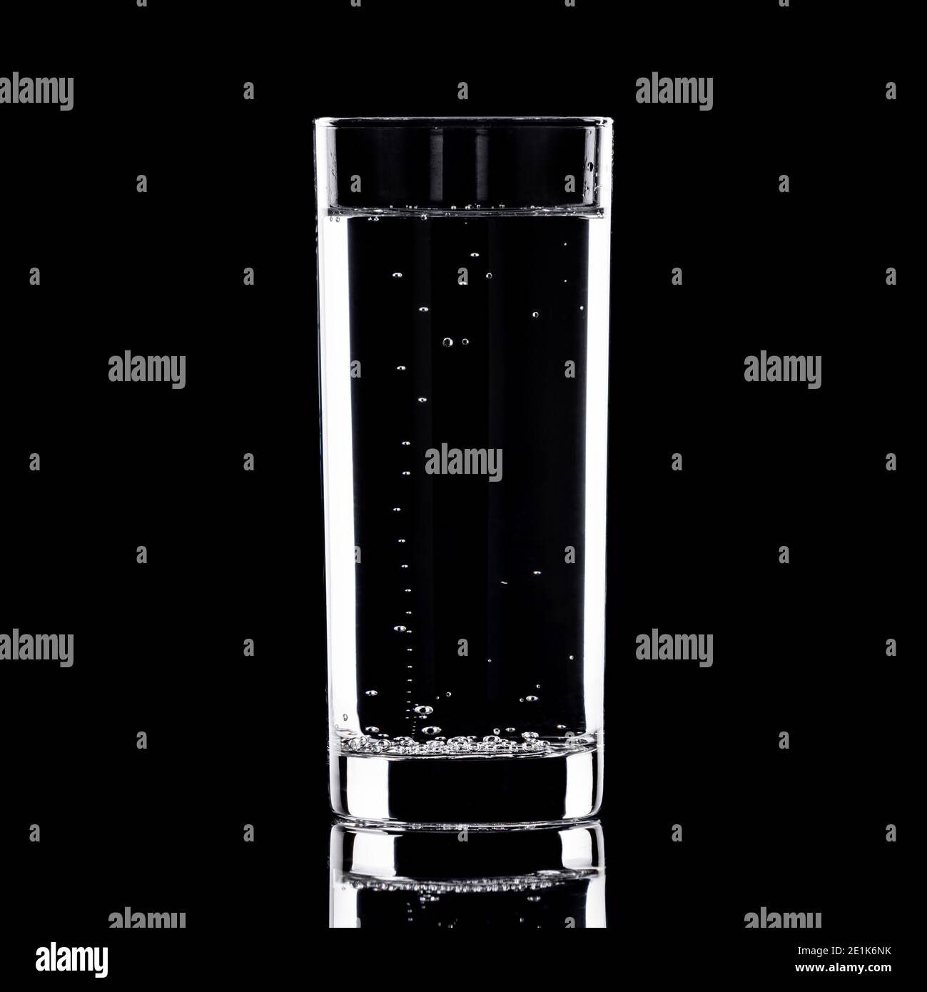 Glas Wasser mit Blasen, die auf schwarzem Hintergrund aufsteigen Stockfoto