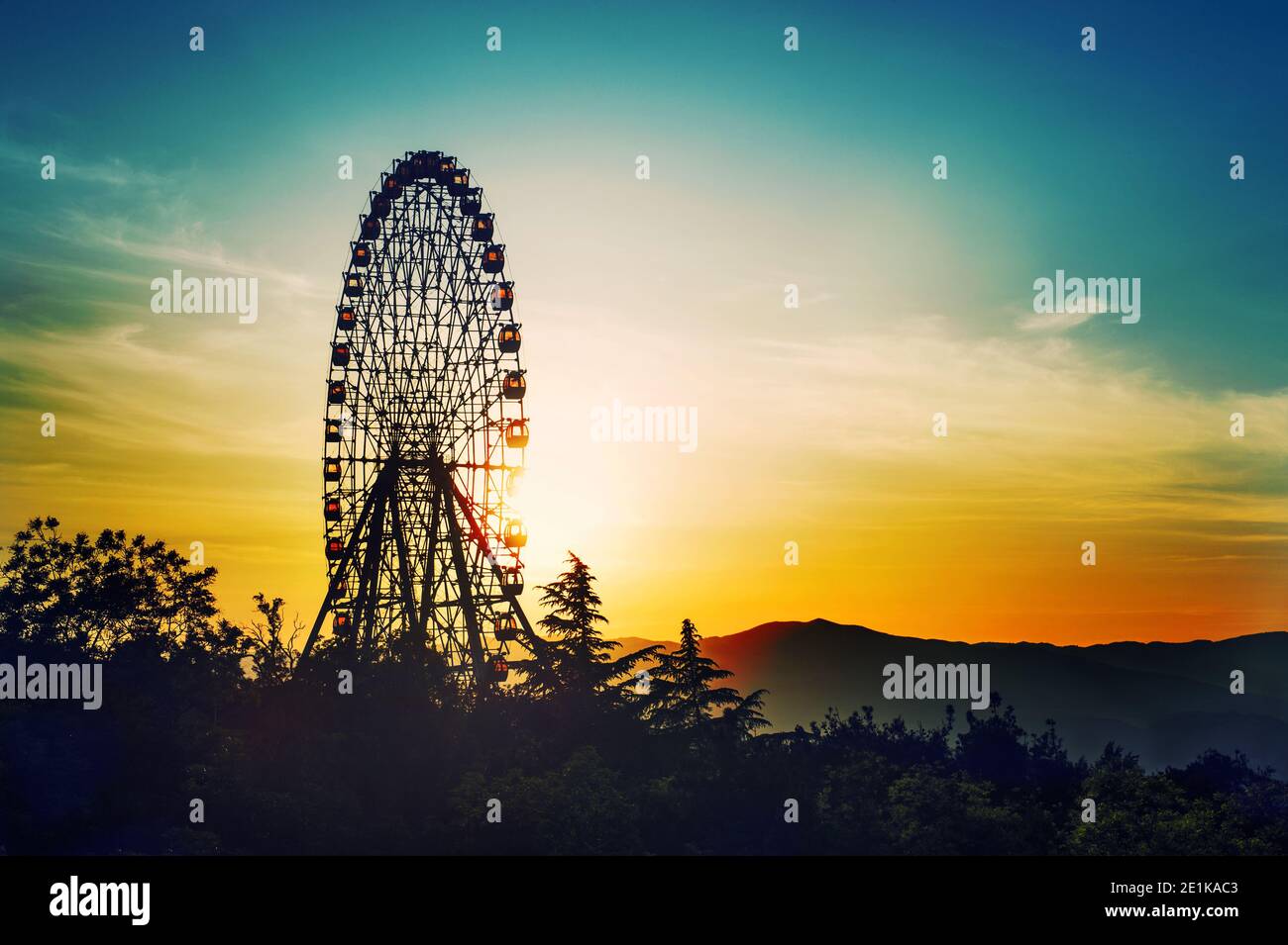 Beobachtungsrad bei Sonnenuntergang über schönem bewölkten Himmel Stockfoto