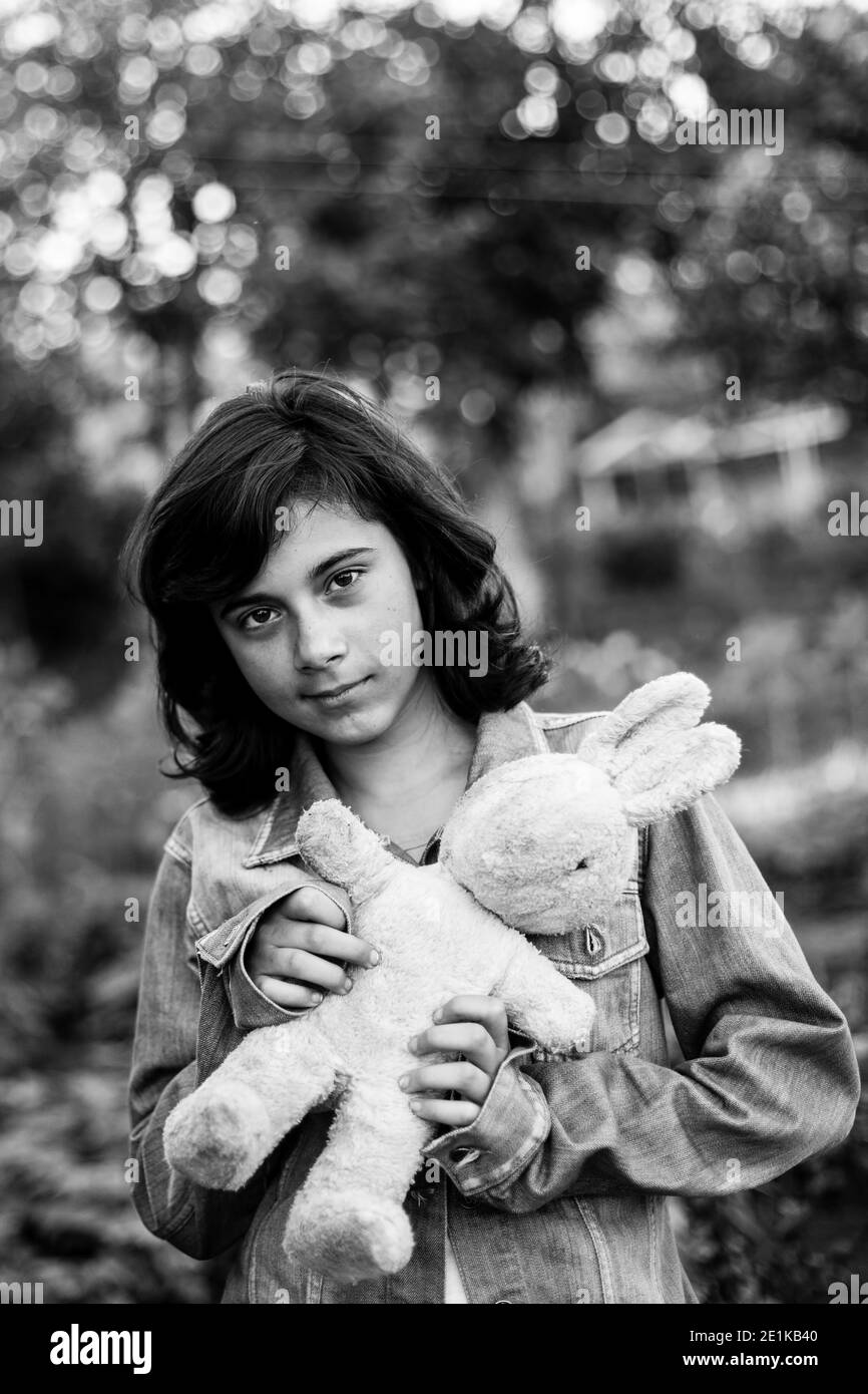 Teen Mädchen in einer Jeansjacke mit einem alten Spielzeug in den Händen, im Freien. Schwarzweiß-Foto. Stockfoto
