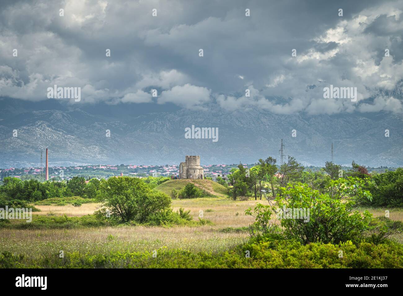 Sandstein St. Nikolaus Kirche mit Dinarischen Alpen im Hintergrund, ist römisch-katholische Kirche zwischen Zaton und Nin in Kroatien Stockfoto