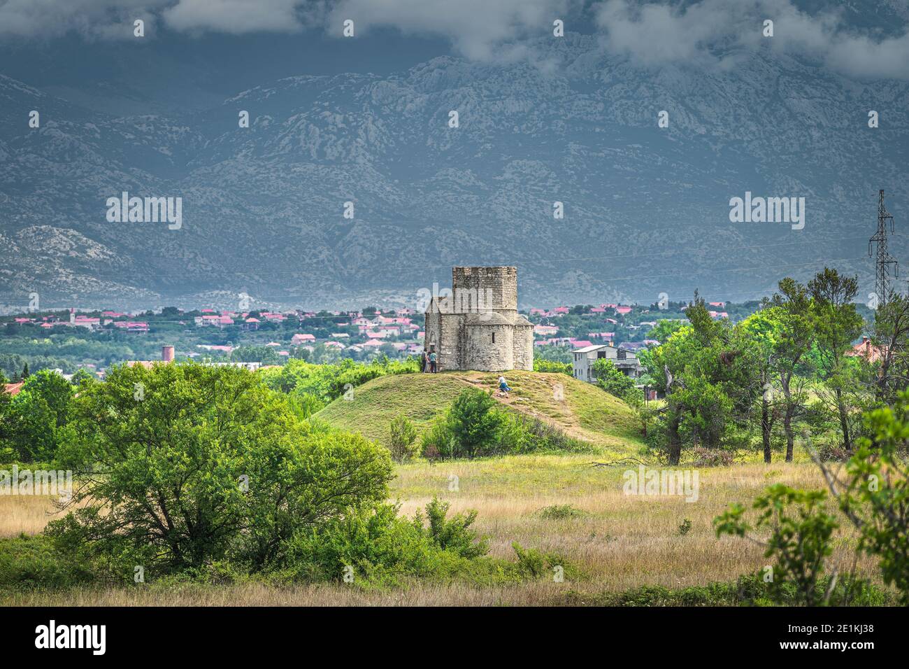Sandstein St. Nikolaus Kirche mit Dinarischen Alpen im Hintergrund, ist römisch-katholische Kirche zwischen Zaton und Nin in Kroatien Stockfoto