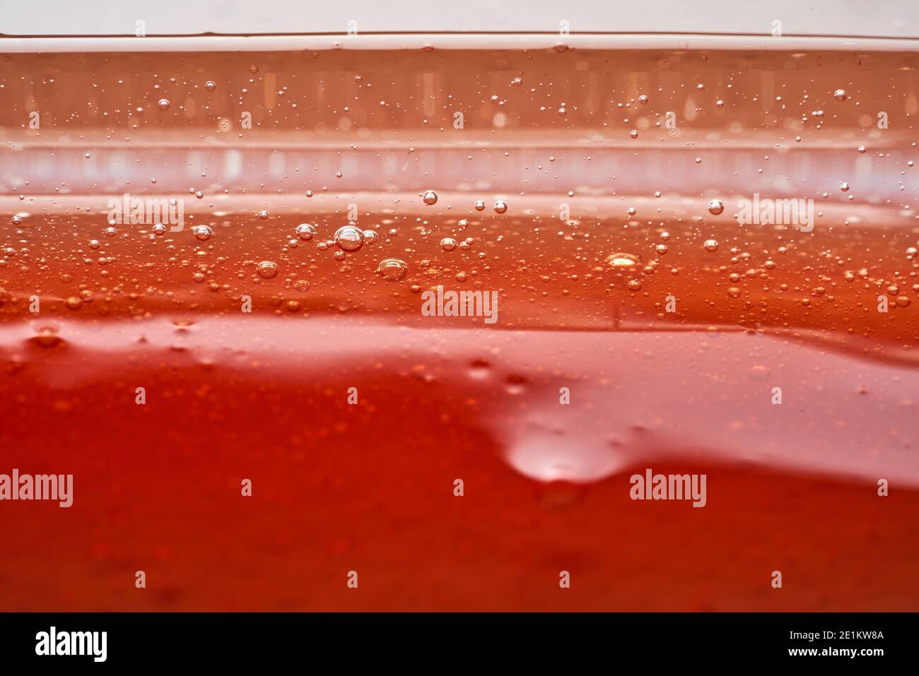 Die Textur des roten transparenten kosmetischen Gels. Abstrakter Hintergrund Stockfoto