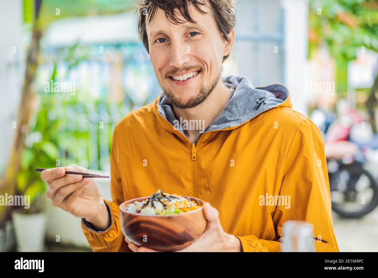 Mann, der rohe organische Poke Schüssel mit Reis und Gemüse Nahaufnahme auf dem Tisch isst. Draufsicht von oben horizontal Stockfoto